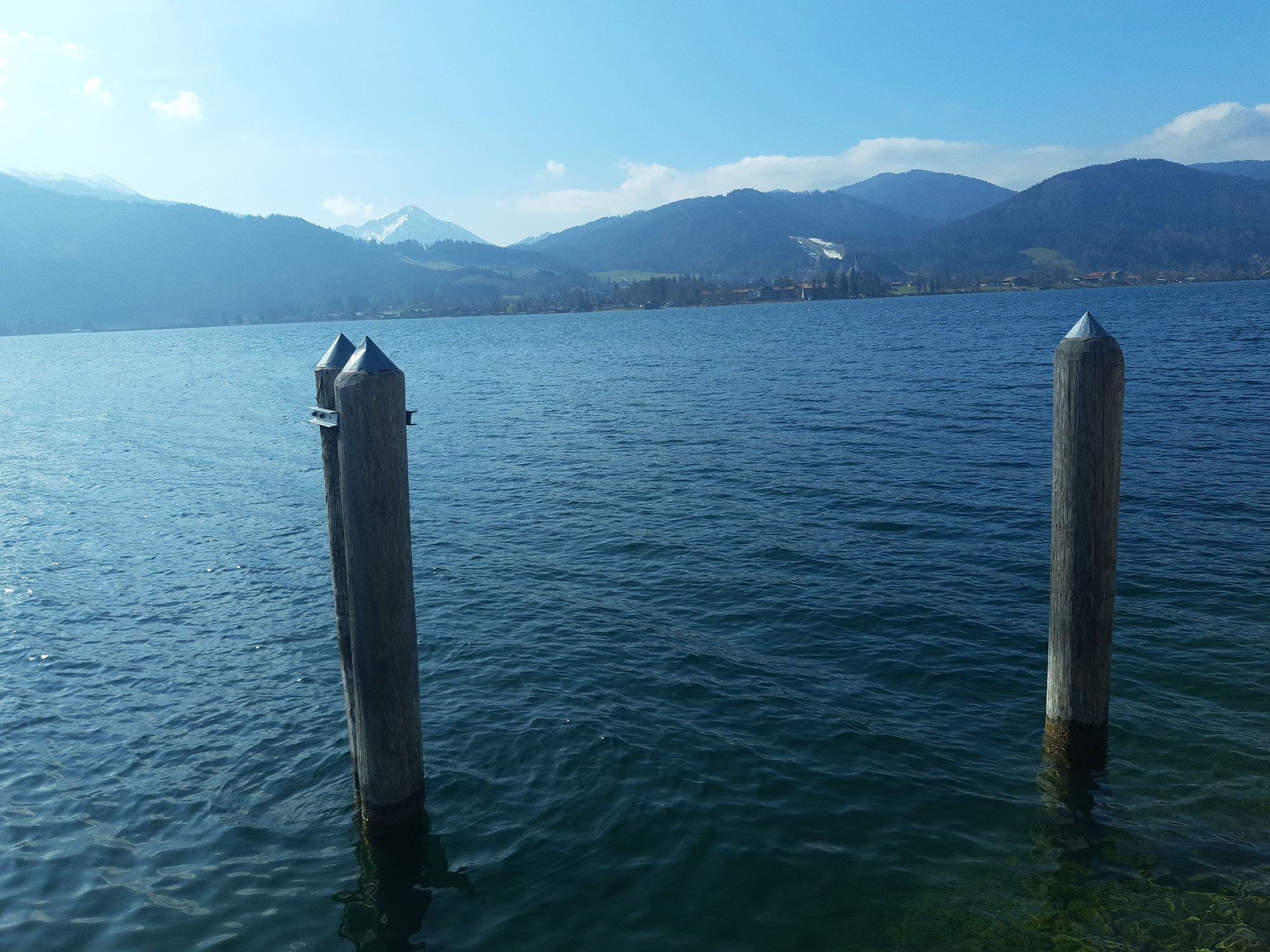 Zwei hölzerne Anlege-Dalben im Tegernsee vor dem Alpenpanorama